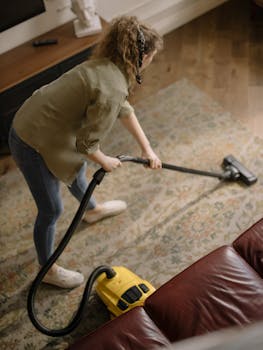 High-angle view of a woman vacuuming a patterned carpet in a stylish living room.